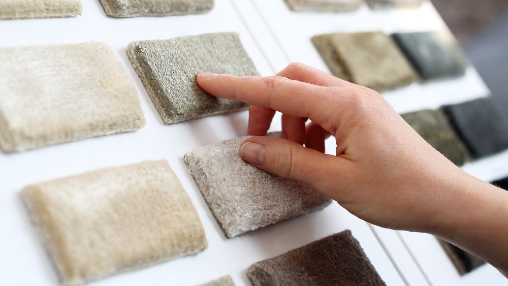 A hand pointing at a selection of carpet samples