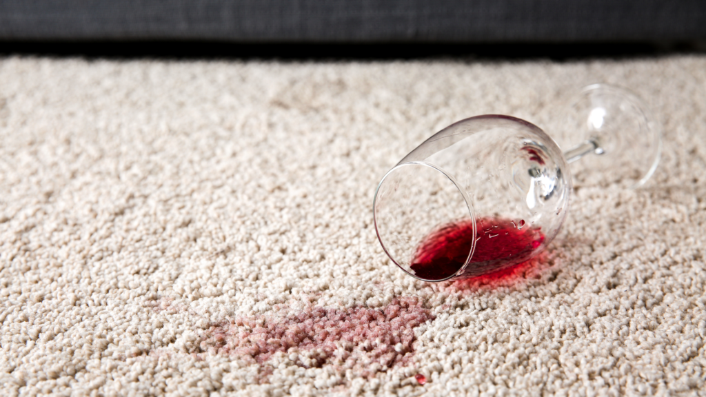 A glass of red wine spilled on a pale beige carpet | Poplar Carpets