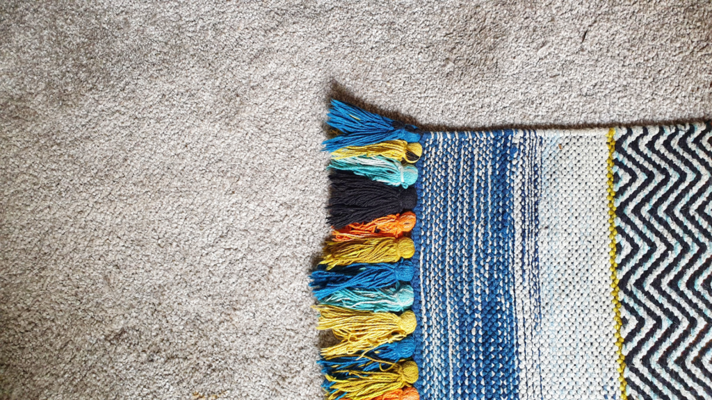A colourful rug placed over a pale carpet for protection | Poplar Carpets